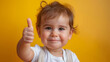 © ChubbyCat - Cheerful toddler giving a thumbs up gesture on a vibrant yellow background.