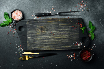 Wall Mural - Vintage wooden cutting board on black stone table. Preparation for cooking. Mockup, free space for text.