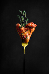 Wall Mural - Traditional Buffalo BBQ chicken wings, on a fork. On a black background.