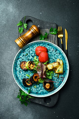Wall Mural - Grilled vegetables on a blue round plate. On a black stone background.