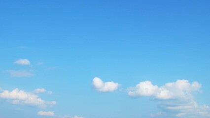 Wall Mural - White cumulus clouds slowly move in the blue summer sky. Background with some clouds and empty space for information.