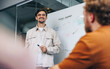 © Jacob Lund - Happy business man standing in front of his colleagues to give a presentation in a meeting