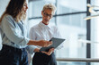 © Jacob Lund - Female executive using a tablet with her assistant in their morning briefing