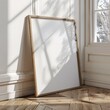 © Larisa - Picture of a wooden frame mockup leaning against a wall in a well-lit room with shadows. Mockup frame. Ratio 3x4.
