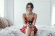 © StockPhotoPro - Woman sitting on the bed and chatting with her phone