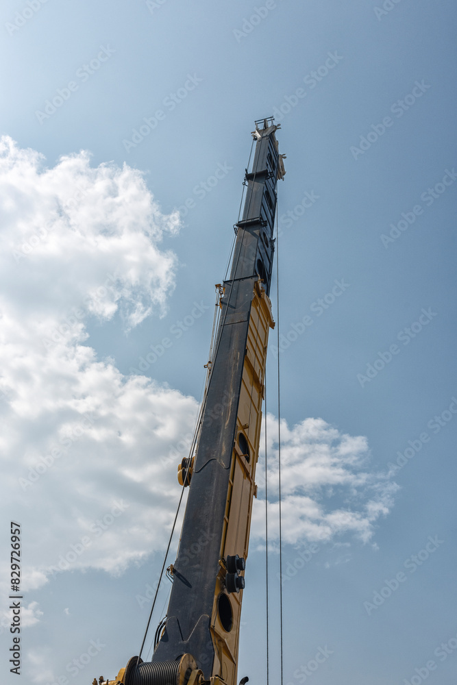 industrial crane that is fully extended stands out against a blue sky