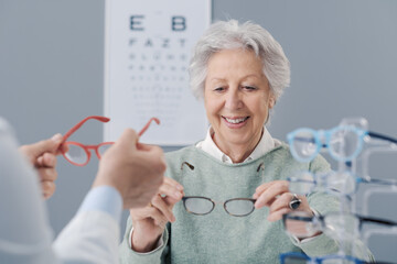 Happy elderly woman choosing new glasses