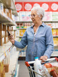 © StockPhotoPro - Senior woman checking supermarket products using her smartphone