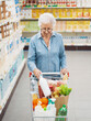 © StockPhotoPro - Senior woman putting goods in the shopping cart