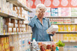 © StockPhotoPro - Senior woman with vision problems reading information on a product package at the supermarket