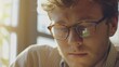 © vefimov - A man wearing glasses is looking at something on a computer screen. Concept of focus and concentration as the man stares intently at the screen. The glasses add a touch of sophistication to the scene