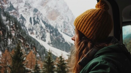 Sticker - A woman wearing a yellow hat is looking out the window of a vehicle. The mountains in the background are covered in snow