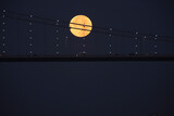 Full moon over Bosphorus bridge at night in Istanbul. The bright and full moon dominates the sky. Perfect for themes related to astronomy, lunar phases, and celestial events.