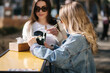 © Aleksandr - Two beautiful blonde and brunette girls order takeaway chinese food. Young woman outdoors speaking. Spring sunny day