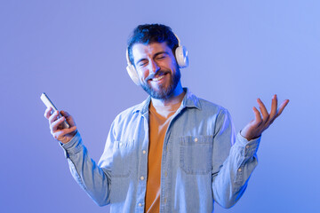 Poster - A man with headphones on his ears is seen holding a cell phone in his hand. He seems focused on the screen, possibly listening to music or a phone call. The background is not visible in the frame.