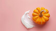 © Sawoon - Flatlay of squash orange pumpkin smear smudge white creamy body skin product cream for Halloween on empty pink table copy space moisturiser anti ageing smooth skincare face mask derma clinic beauty