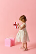 © LIGHTFIELD STUDIOS - Little girl in white dress joyfully holds a pink gift box.