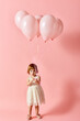© LIGHTFIELD STUDIOS - Adorable girl in white dress holding pink balloons on a pink background.
