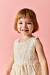 © LIGHTFIELD STUDIOS - Little girl in white dress posing for a portrait on a pink backdrop.