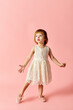© LIGHTFIELD STUDIOS - Little girl in white dress strikes a pose on a vivid pink background.