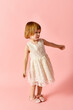 © LIGHTFIELD STUDIOS - Little girl in white dress posing on pink background.