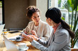 © Marko Geber - Two professional women discussing work at a cafe table