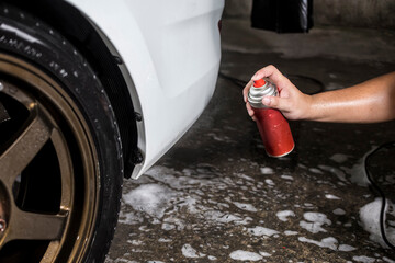 Wall Mural - Spraying a pitch cleaner on the back of the wheels and chassis to remove small scratches, dead bugs, tar, and other oily dirt.