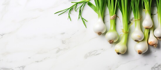 Poster - A cluster of fresh green spring onions arranged on a white marble surface captured from above This flat lay composition offers ample space for adding text