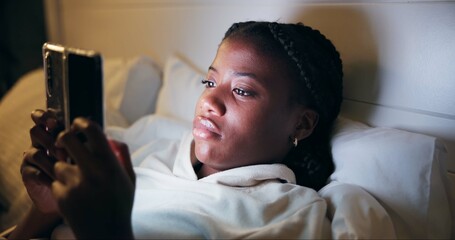Fototapete - Night, typing and black woman with phone on bed for online chat, communication and networking. Resting, home and tired person on smartphone for social media, website and internet news in bedroom