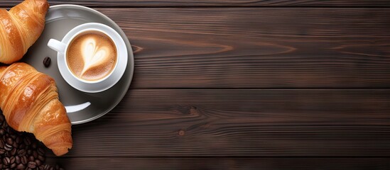 Wall Mural - A copy space image featuring a cup of coffee and a croissant placed on a wooden background