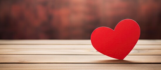 Poster - A heart shaped paper in red is placed on a wooden table creating a perfect area to add additional images or text
