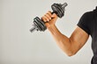 © LIGHTFIELD STUDIOS - A young sportsman in active wear grips a pair of dumbbells, focusing on his workout in a grey background studio.