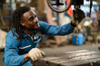 © KANGWANS - A man with dreadlocks is looking at a drill. The man is wearing a blue shirt and a blue jacket