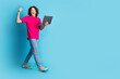 © deagreez - Full length portrait of nice young man walk netbook thumb up empty space wear t-shirt isolated on blue color background