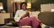 © peopleimages.com - Black girl, happy and smartphone on sofa in home scrolling or online social media memes, videos and funny text. Woman, texting and mobile on couch to relax with entertainment, streaming and internet.