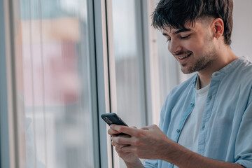 Canvas Print - young man with mobile phone indoors next to the window