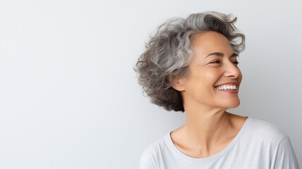 Poster - Portrait of beautiful happy smiling mature woman with toothy smile on white studio background