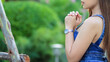 © thatinchan - young woman clasped her hands together in prayer asking for forgiveness from God based on her Christian beliefs and faith in God teachings. concept prayer and intercession according beliefs about God