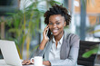 © paco - Smiling Businesswoman on the Phone. Cheerful African American businesswoman wearing glasses, talking on the phone while working on her laptop in a modern office environment.