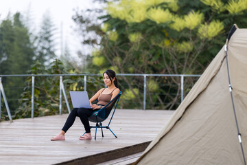 woman work on laptop computer with camp tent