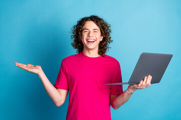 Poster - Portrait of nice young man arm hold laptop empty space wear pink t-shirt isolated on blue color background