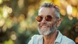 © progressman - a man with a beard and glasses smiling for the camera with a blurry background of trees and bushes..