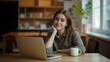 © SFotoz - Woman sitting at a table with a laptop and a mug, working remotely in a home setting.