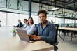 © Barry - Young, black man working at a tech startup company as part of a diverse team. Using laptop in modern, open plan office.