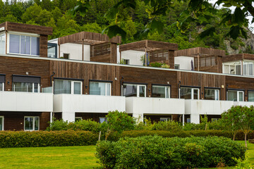 Wall Mural - Row of apartments in front of a green forest clad hill.