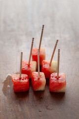 Wall Mural - Close-up of Watermelon (Citrullus Lanatus) fruit Cubes with bamboo sticks, on a wooden background.