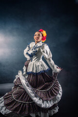 Wall Mural - A woman in a colorful dress is dancing in front of a dark background