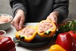© New Africa - Woman making stuffed peppers with ground meat at white table, closeup