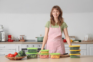Wall Mural - Beautiful young woman and plastic containers with vegetables for freezing on table in kitchen