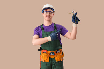 Poster - Male electrician pointing at cables on brown background